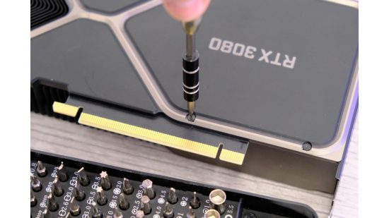 A screwdriver removing backplate screws from the RTX 3080 GPU