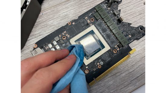 The RTX 3080 GPU die, a hand is cleaning it of thermal paste