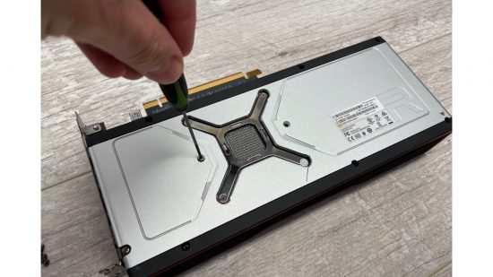 A screwdriver removing screws from an AMD Radeon RX 6800 XT GPU
