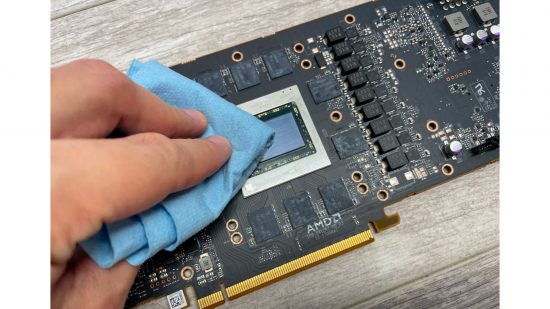 A hand cleaning thermal paste from the GPU die on an AMD Radeon RX 6800 XT GPU