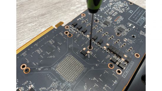 A screwdriver tightening screws on an AMD Radeon RX 6800 XT GPU